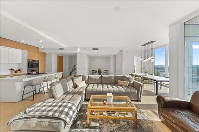 Living room with light wood-style flooring, floor to ceiling windows, and a chandelier