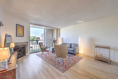 Living area featuring expansive windows, light wood-style flooring, a textured ceiling, and a fireplace