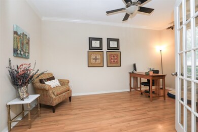 French doors off of the entry open to reveal a handsome and light-filled home office graced with wood floors and ceiling fan.