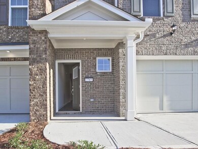 Doorway to property with driveway, brick siding, and an attached garage