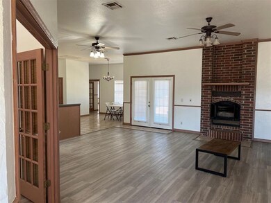 Unfurnished living room featuring visible vents, french doors, ceiling fan with notable chandelier, and wood finished floors