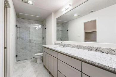 Bathroom featuring walk in shower, vanity, and toi