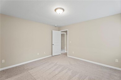 Unfurnished room featuring light carpet, baseboards, and a textured ceiling