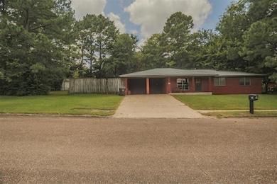 View of front facade with concrete driveway, brick siding, and view of wooded area