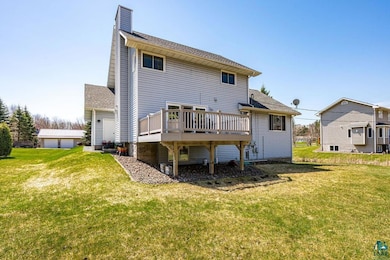 Back of house featuring a deck, a chimney, a yard,