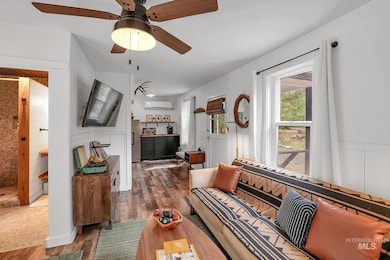 Living area featuring an AC wall unit, wood finished floors, and a ceiling fan