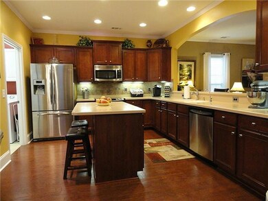 Kitchen with hardwood floor, stainless appliances, attractive countertops and can lighting.