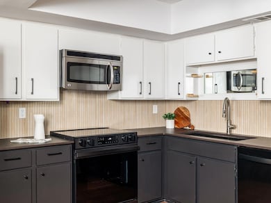 Kitchen with a sink, gray cabinetry, black applia