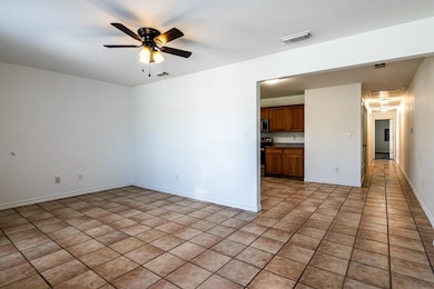 Empty room featuring ceiling fan and light tile pa