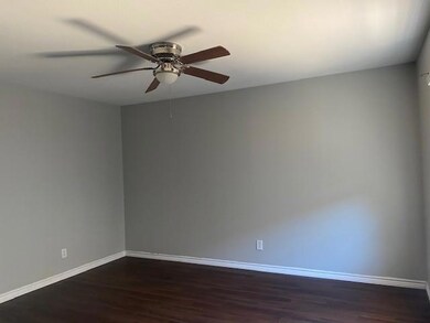 Empty room with ceiling fan and dark wood-type flooring
