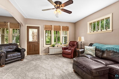 Carpeted living room with ceiling fan and radiator