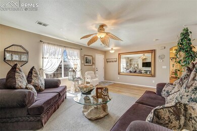 Living area featuring baseboards, a textured ceiling, visible vents, ceiling fan, and wood finished floors
