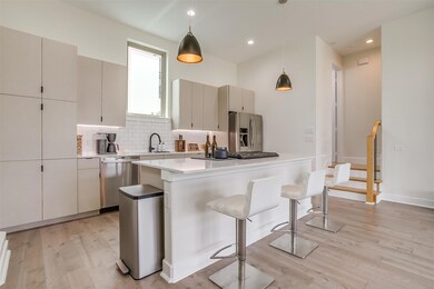 Kitchen with stainless steel appliances, decorative backsplash, a breakfast bar, decorative light fixtures, and large island