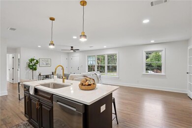 Kitchen with dark brown cabinetry, open floor plan, stainless steel dishwasher, dark wood-type flooring, and pendant lighting