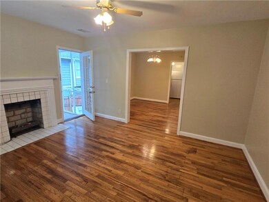 Unfurnished living room with wood finished floors, a tile fireplace, baseboards, and a ceiling fan