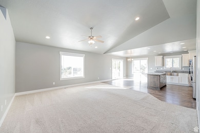 Unfurnished living room with vaulted ceiling, a chandelier, a ceiling fan, recessed lighting, and a textured ceiling