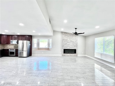 Unfurnished living room featuring a ceiling fan, recessed lighting, a stone fireplace, and vaulted ceiling