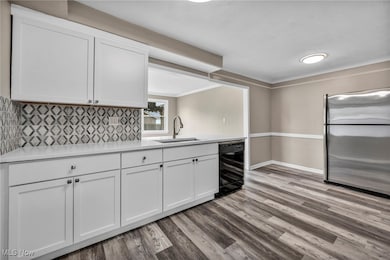 Kitchen with freestanding refrigerator, backsplash, ornamental molding, and white cabinetry