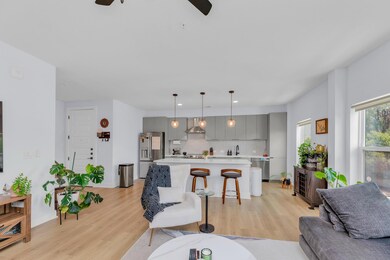 Living area featuring a ceiling fan, light wood f