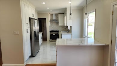 Kitchen with wall chimney exhaust hood, white cabinets, recessed lighting, black / electric stove, and stainless steel fridge with ice dispenser