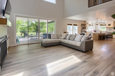 Living room with light wood-style flooring, a high ceiling, recessed lighting, and a fireplace