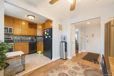 Kitchen featuring brown cabinets, light wood-type flooring, backsplash, a heating unit, and black appliances
