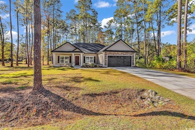 View of front of house with driveway, a front lawn, an attached garage, board and batten siding, and stone siding