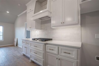 Kitchen with white cabinetry, custom range hood, s