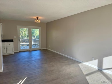 Unfurnished dining area featuring dark wood-style flooring and a textured ceiling
