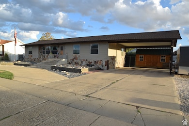 View of front of home with driveway, a shed, and roof with shingles