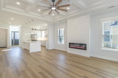 Unfurnished living room with a fireplace, coffered ceiling, visible vents, and a healthy amount of sunlight