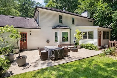 Back of property featuring a chimney, a patio area, an outdoor hangout area, and a lawn