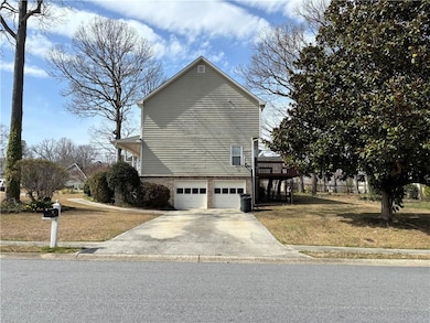 View of home's attached garage, a lawn, and concre