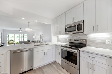 Kitchen featuring appliances with stainless steel finishes, a sink, light countertops, decorative backsplash, and recessed lighting
