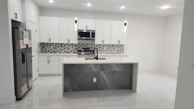 Kitchen with tasteful backsplash, sink, white cabi