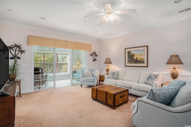 Carpeted living area with ornamental molding and c