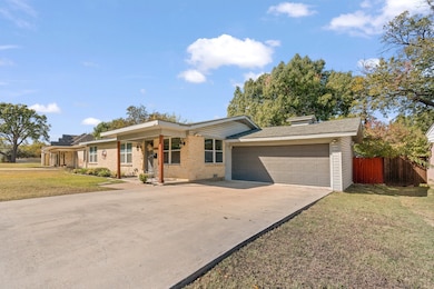Ranch-style home with concrete driveway, an attached garage, roof with shingles, a porch, and brick siding