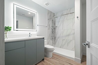 Bathroom with toilet, a tile shower, vanity, and 