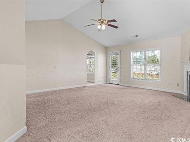 Unfurnished living room featuring light carpet, arched walkways, high vaulted ceiling, a fireplace with flush hearth, and ceiling fan