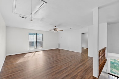 Unfurnished living room with attic access and dark wood-style flooring