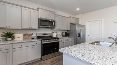 Kitchen with gray cabinetry, light stone counterto