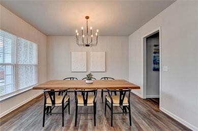 Dining area with a chandelier, baseboards, and dark wood-style flooring
