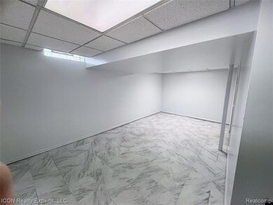 Empty room featuring a drop ceiling and baseboards