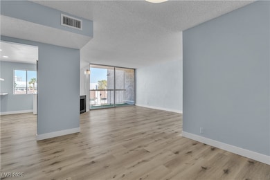 Unfurnished room featuring healthy amount of natural light, a textured ceiling, wood finished floors, and floor to ceiling windows