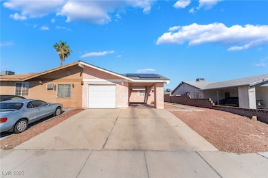 Ranch-style home featuring stucco siding, concrete driveway, roof mounted solar panels, and an attached garage