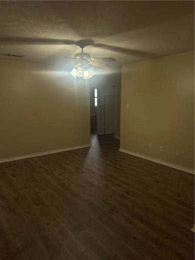 Empty room with dark wood-style flooring and a cei