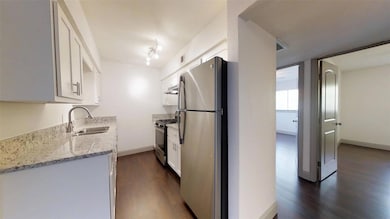 Kitchen with white cabinets, sink, light stone cou