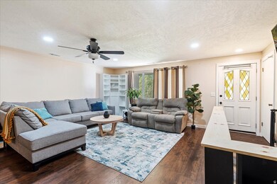 Living area featuring dark wood-style flooring, a textured ceiling, crown molding, recessed lighting, and ceiling fan