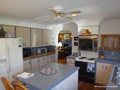 Kitchen w/ pass-through window to formal dining room & segmented archway.