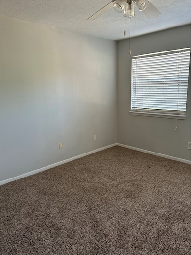 Carpeted spare room featuring ceiling fan, a textu